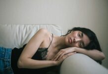 만성피로, 단순한 피로와 다르다…현대인의 건강 적신호 woman wearing black spaghetti-strap tank top and blue denim bottoms lying on sofa