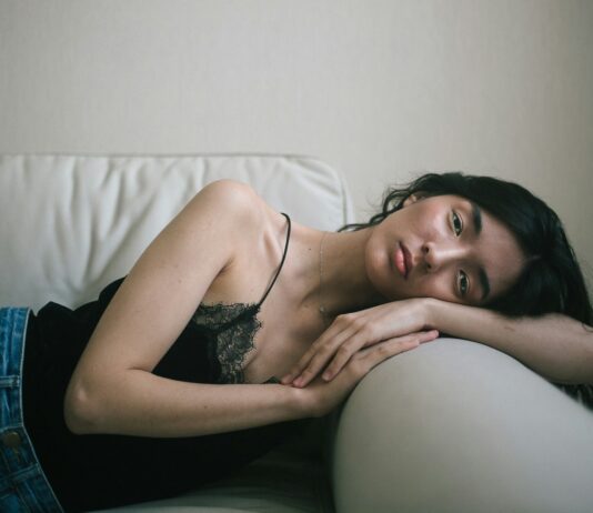 만성피로, 단순한 피로와 다르다…현대인의 건강 적신호 woman wearing black spaghetti-strap tank top and blue denim bottoms lying on sofa