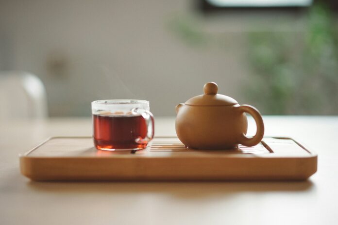 Photo by Manki Kim clear glass cup with tea near brown ceramic teapot
