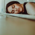 “끊이지 않는 피곤함, 만성피로 극복을 위한 생활 속 신선한 변화” woman resting her head on brown wooden panel bed while closing her eyes