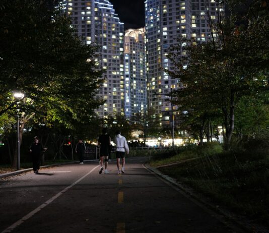 ‘마음챙김 걷기’, 일상 속 활력 더하는 새로운 건강 습관 People jogging on a path at night near apartments.