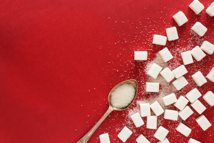 Photo by Elena Leya sugar cubes and a spoon on a red surface